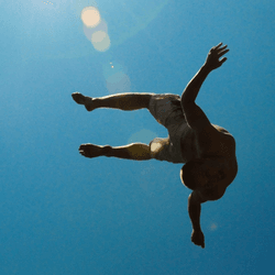 Man diving through the air, appearing to float, with a sunny blue sky background