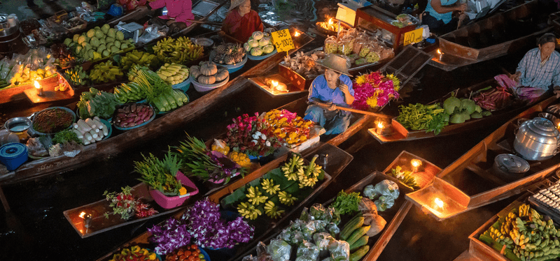 The merchant in wooden boat made alms to the monk at Damnoen Saduak Floating Market the tourists by boat popular tourist attraction on canals of Thailand