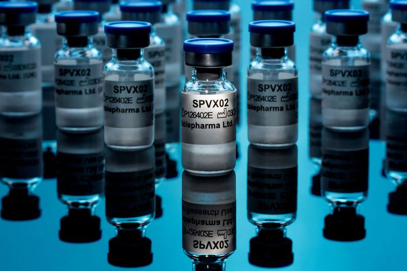 vials of vaccine on a reflective surface, with a spotlight on the front one so that the label "SPVX02" is visible
