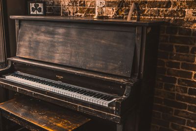 vintage-looking upright piano against a brick wall