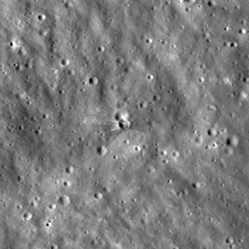 the cratered surface of the Moon and in the middle two overlapping crater with one of them showing fresh streaks of dark and bright material