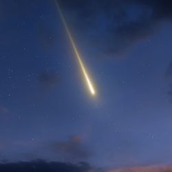 a fireball in the evening sky, appearing among some clouds