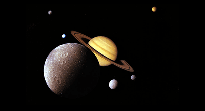 This famous Voyager image contains Dione (forefront), Tethys and Mimas (lower right), Enceladus and Rhea (upper left) and Titan in distant orbit (upper right), but these days two of them dominate our attention