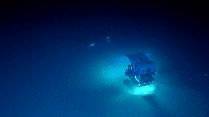 an rov scanning the dark waters along the seabed finds square shapes in the distance