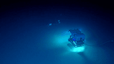 an rov scanning the dark waters along the seabed finds square shapes in the distance