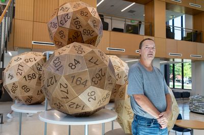 Eric Harshbarger stands with his five giant 60-sided dice, each measuring roughly 3.5 feet across.