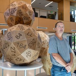 Eric Harshbarger stands with his five giant 60-sided dice, each measuring roughly 3.5 feet across.