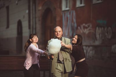 a man eating cotton candy as two young girls trying to pick some
