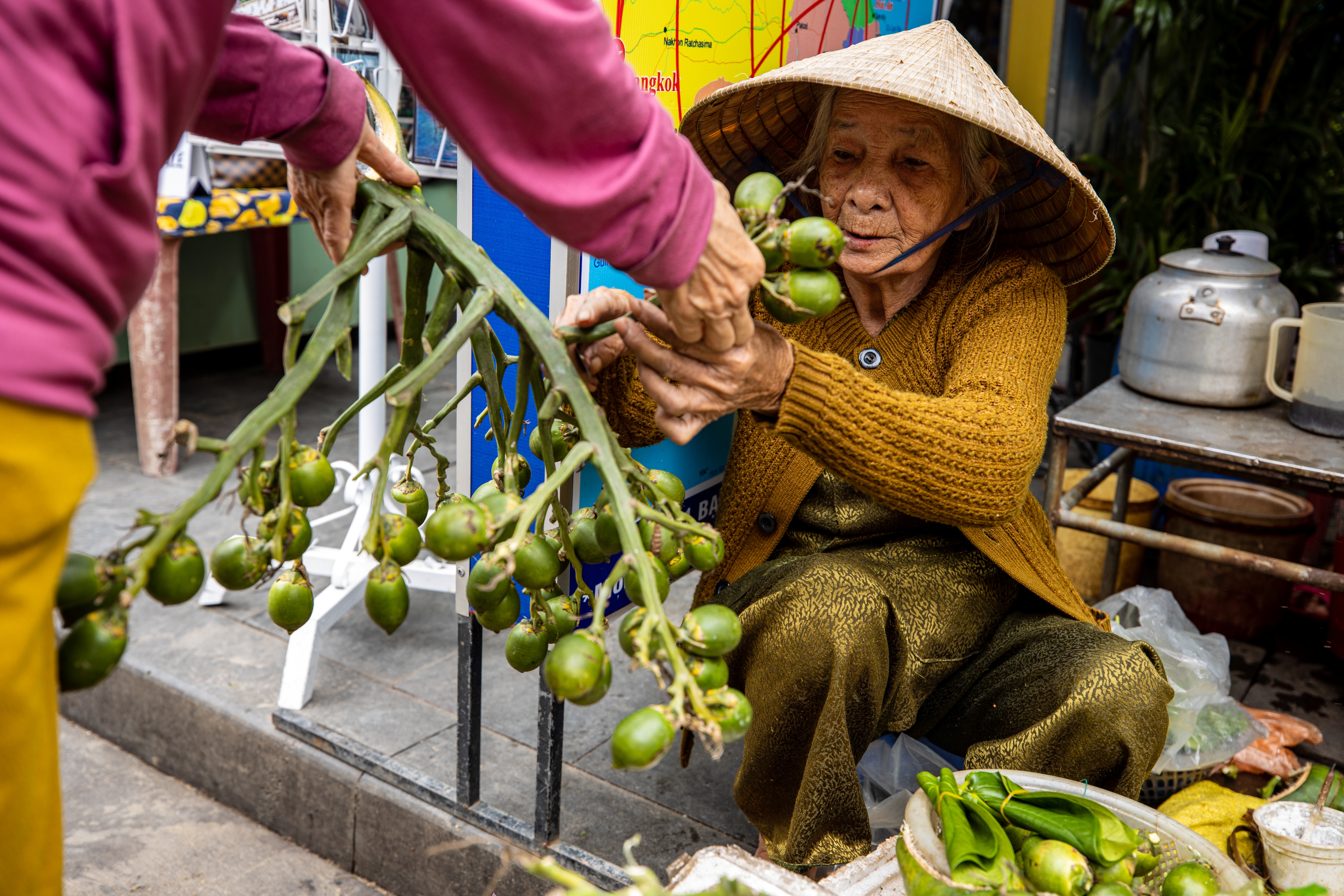 elderly woman selling betel nuts at a market in vietnam
