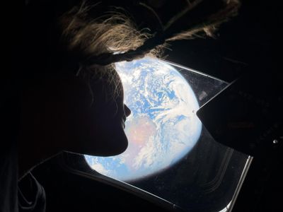 NASA astronaut Christina Koch, the first woman to ever travel beyond Earth’s orbit in 2026, looks back at a seemingly spherical Earth from the Orion spacecraft.