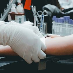 A phlebotomists takes a blood sample from a patient arm.
