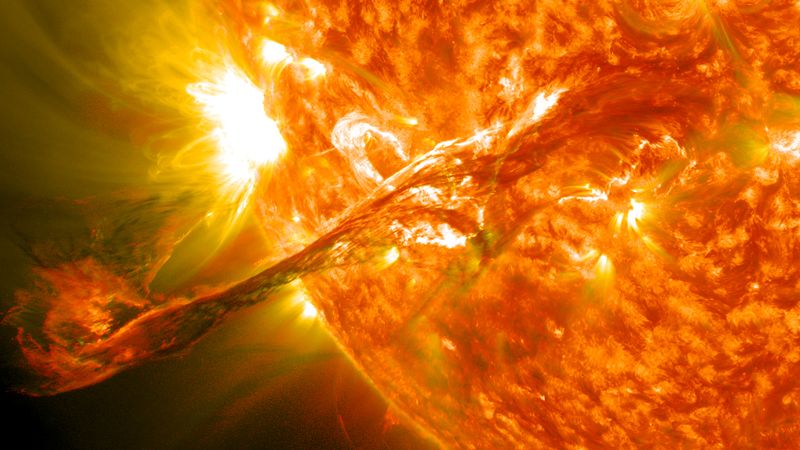 a partial view of the Sun showing a large plasma filament and a bright region at the rim of the solar disk