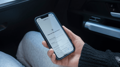 A phone loaded with ChatGPT, held by a hand in a car.