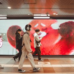People walking in front of a huge LED monitor screen at Shibuya Station in Tokyo, Japan.