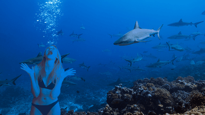 a woman underwater screaming near sharks