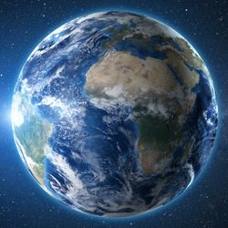 Earth from space with the sun rise peeking out behind 