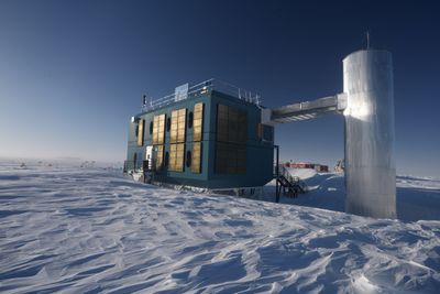 A boxy bulding connected to a cylindrical structure over the icy landscape of Antarctica