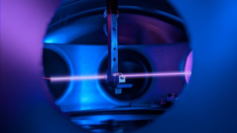 a metal hook holds a little crystal as a laser light shines through it