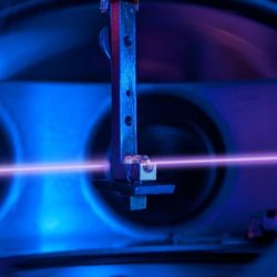 a metal hook holds a little crystal as a laser light shines through it
