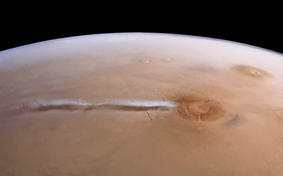 Tan-coloured horizontal rectangle showing part of the surface of Mars imaged by an orbiting satellite. Above the curved horizon is space. To the lower right of the image is a volcano. Stretching to the left of the volcano is a long wisp of white cloud, which seems to emanate from the volcano. We also see the shadow of the cloud just below the cloud itself.