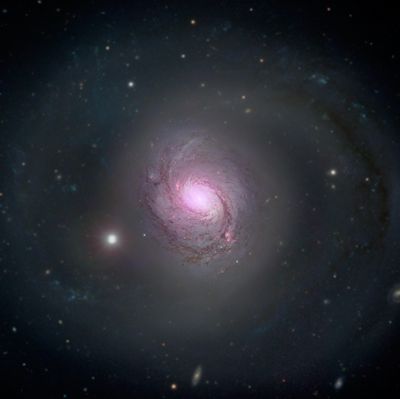 the galaxy is a traditional spiral galaxy with two long spiral arms and an elongated core. The central region is a bright magenta