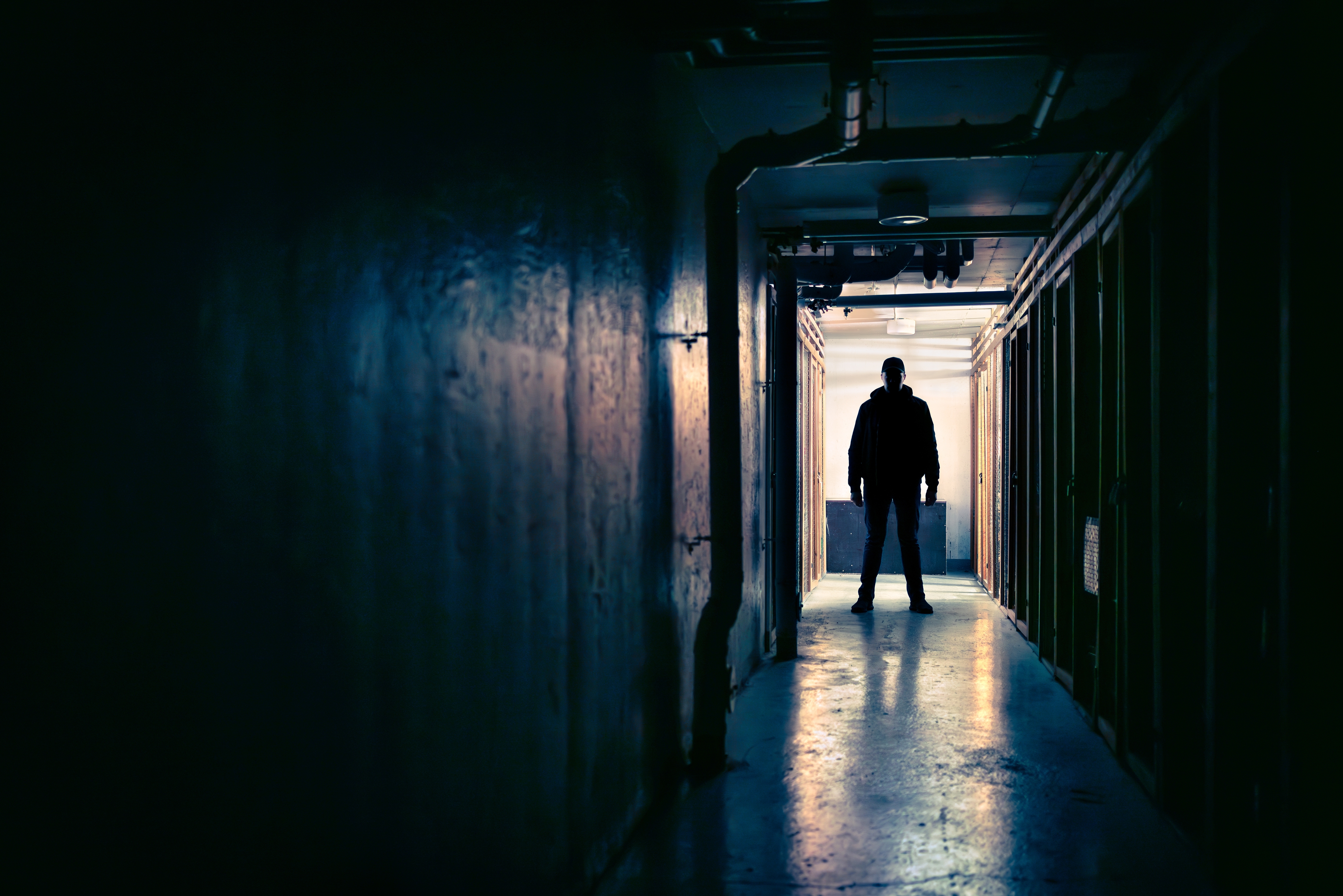 The silhouette of a man standing at the end of a dark corridor. The silhouette of a man standing at the end of a dark corridor.