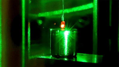 A diamond suspended by a graphite rod, above a magnet.